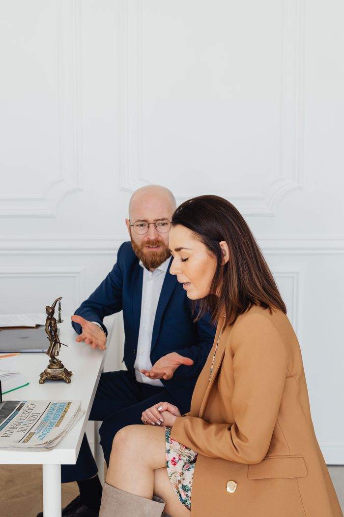 A man and woman engage in an emotional conversation in an office, symbolizing communication challenges.